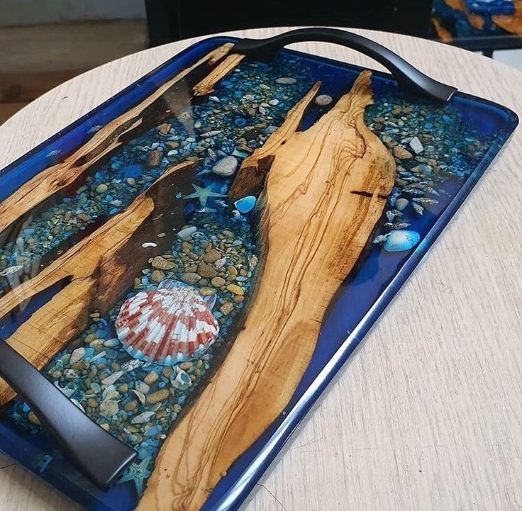 there is a blue tray that has some wood and shells in it on the table