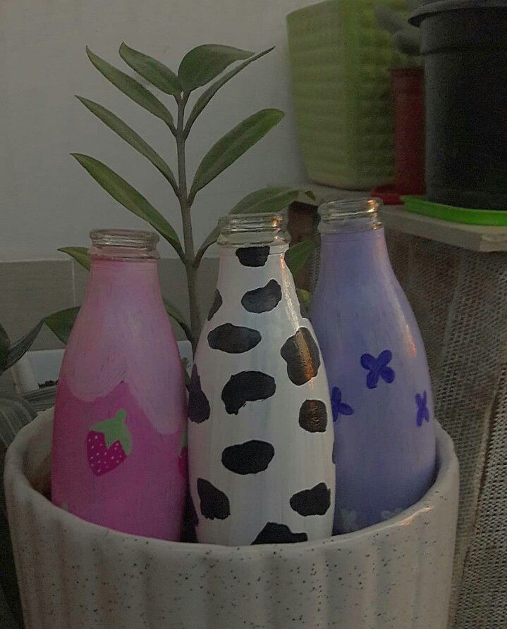 three painted milk bottles in a white bowl