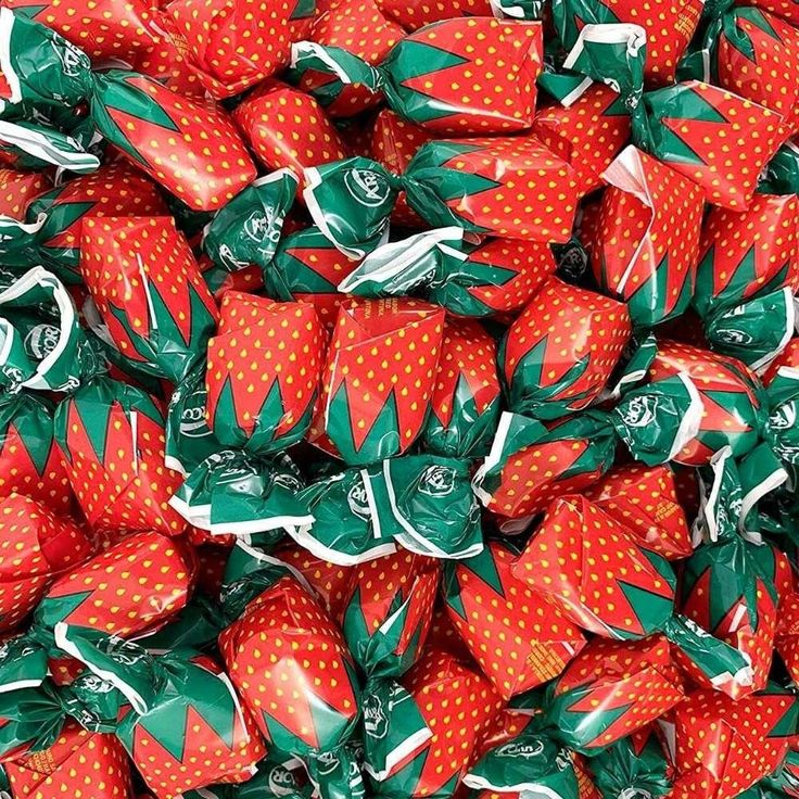 a pile of strawberries with green and red wrappers on top of each one