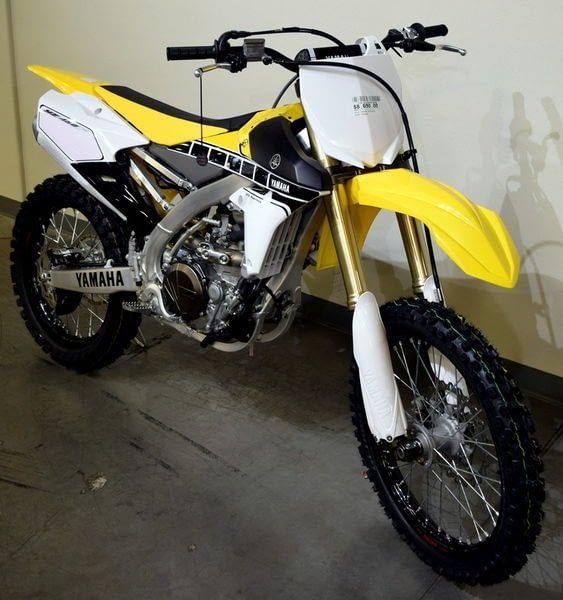 a yellow and white dirt bike parked next to a wall