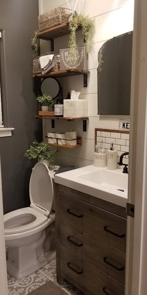 a white toilet sitting in a bathroom next to a wooden shelf filled with boxes and plants