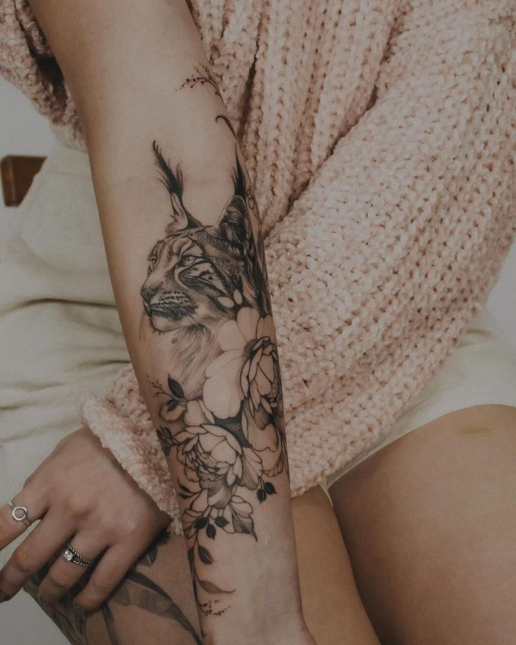 Realistic Animal Portrait2 Arm tattoo of a lynx with floral accents in black ink. Cozy beige sweater in the background. | Sky Rye Design