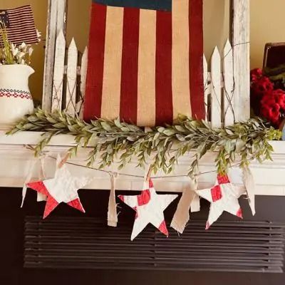 an american flag is hanging on the mantle in front of a mantel with wreaths and garland