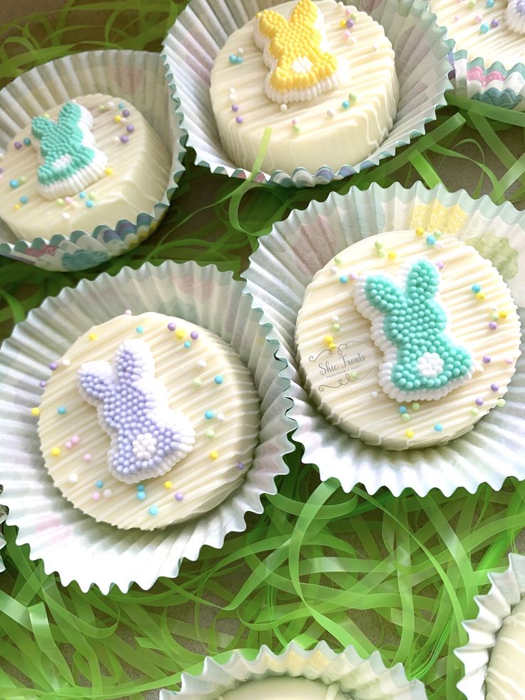 some cupcakes with icing and decorations on them sitting in paper cups next to green grass