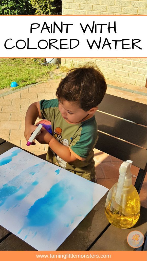 a young boy is painting with colored water