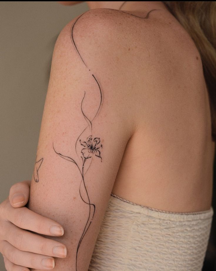 a woman's arm with a flower tattoo on the left side of her arm