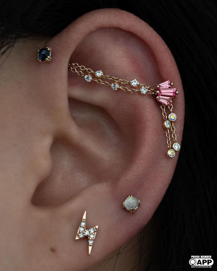 an ear with some piercings attached to it's sides and two different colored stones