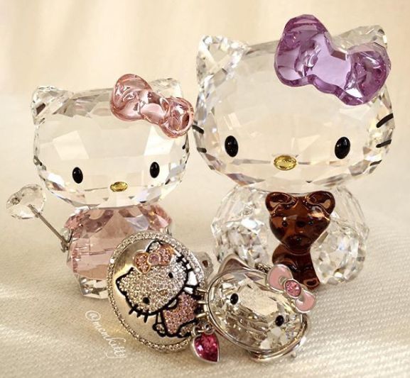 two hello kitty figurines sitting next to each other on a white cloth covered surface