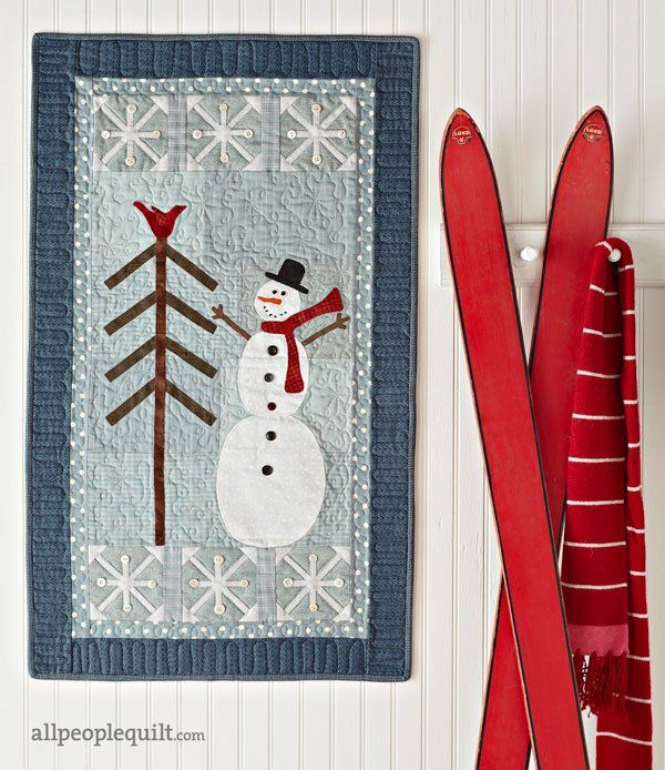 two red skis are next to a wall hanging with a snowman on it