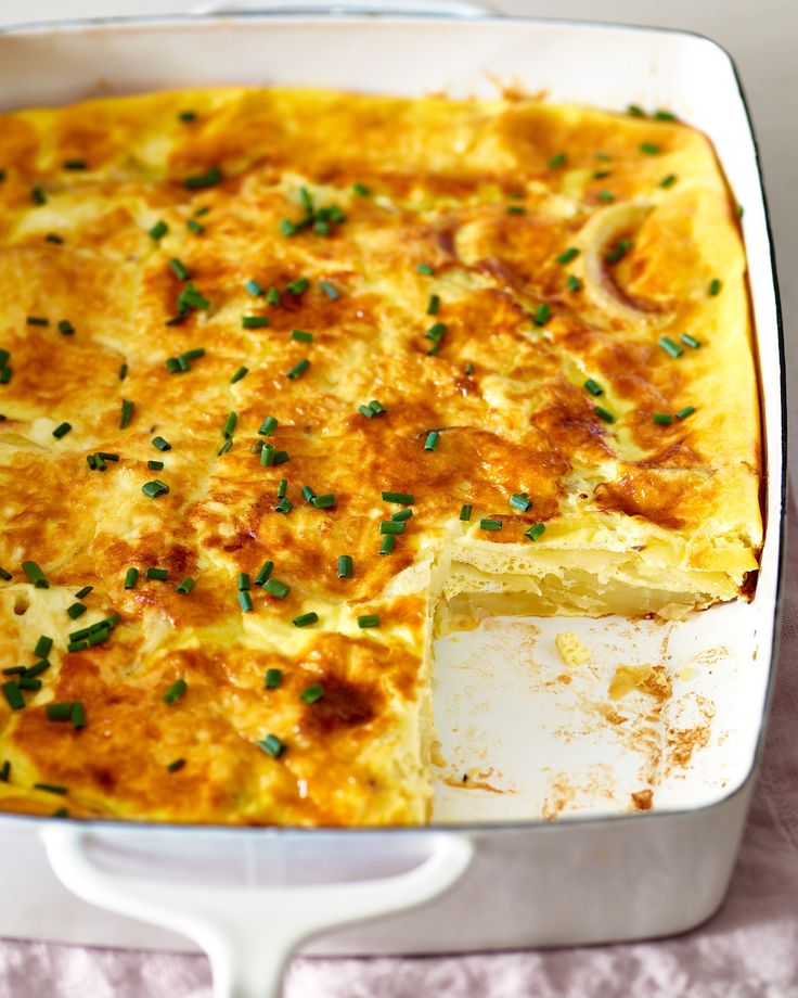 a casserole with cheese and green onions in a white dish on a table