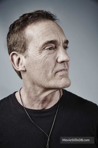 a man in black shirt looking off into the distance with his head tilted to the side