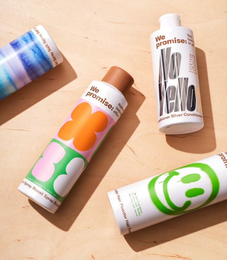 three tube containers sitting on top of a wooden table next to each other with different logos