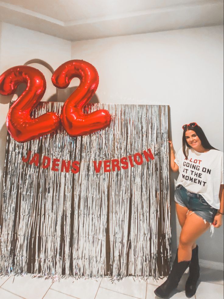 a woman standing in front of a sign that says twenty two years old with red balloons