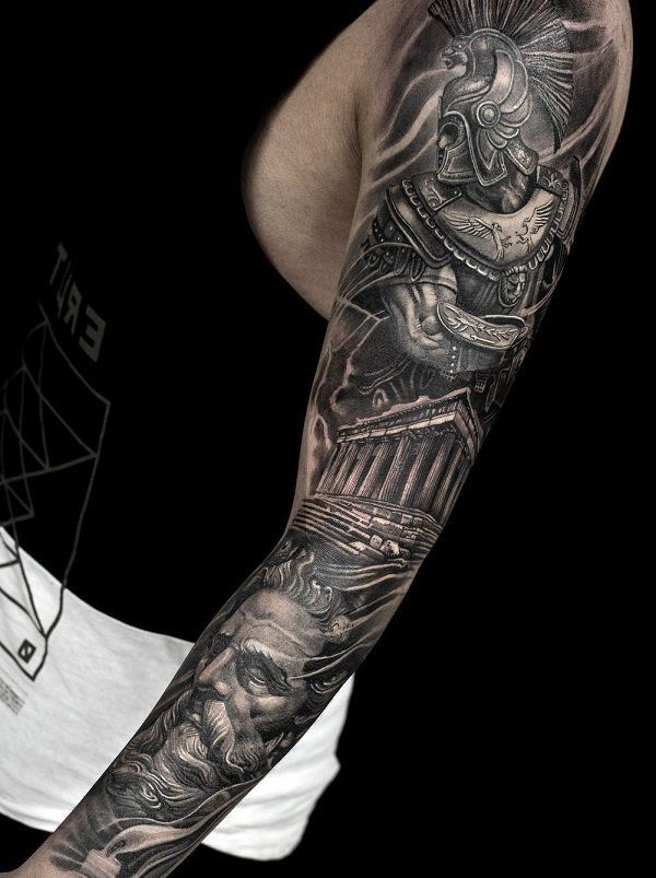 a man's arm with tattoos on it and an image of a statue in the background