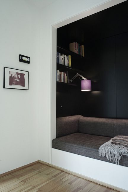 a room with a couch, bookshelf and pictures on the wall