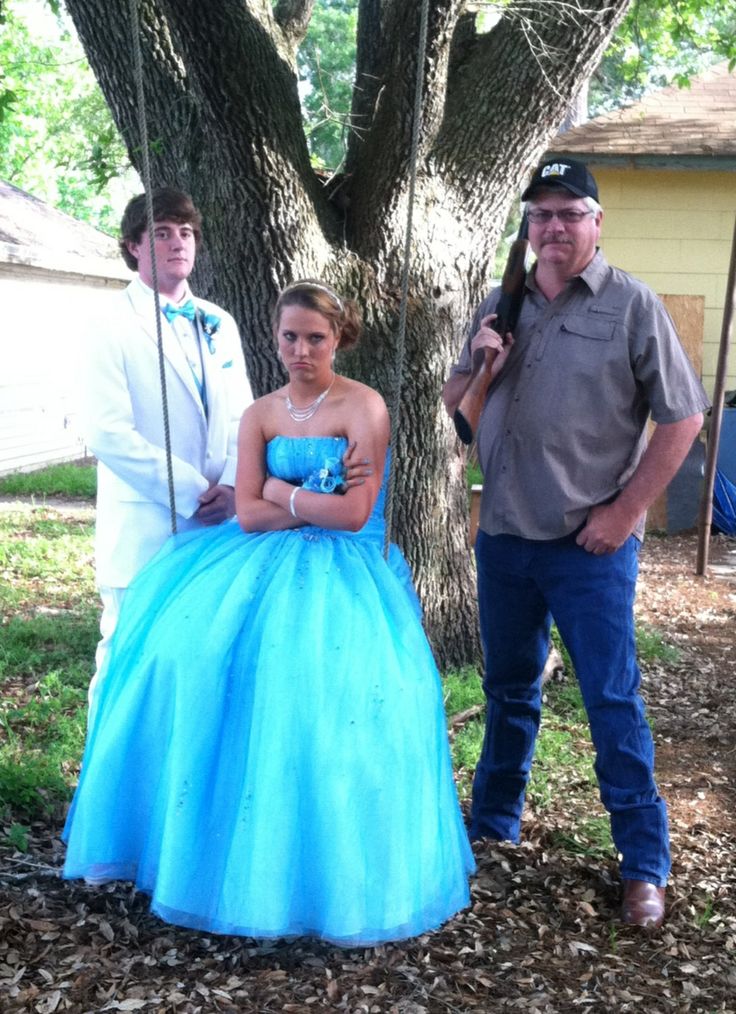 two men and a woman standing in front of a tree with a blue dress on