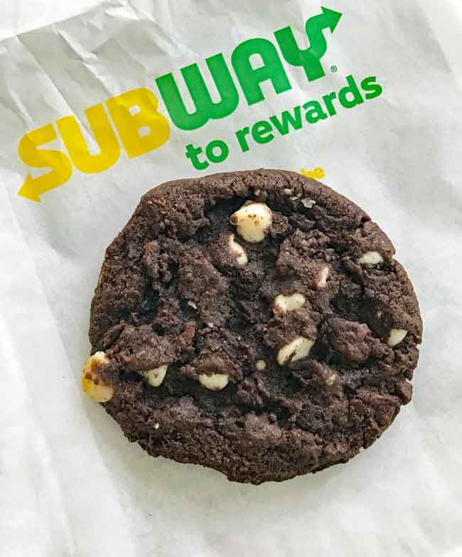 a close up of a chocolate cookie on a paper bag with the subway to reward logo in the background