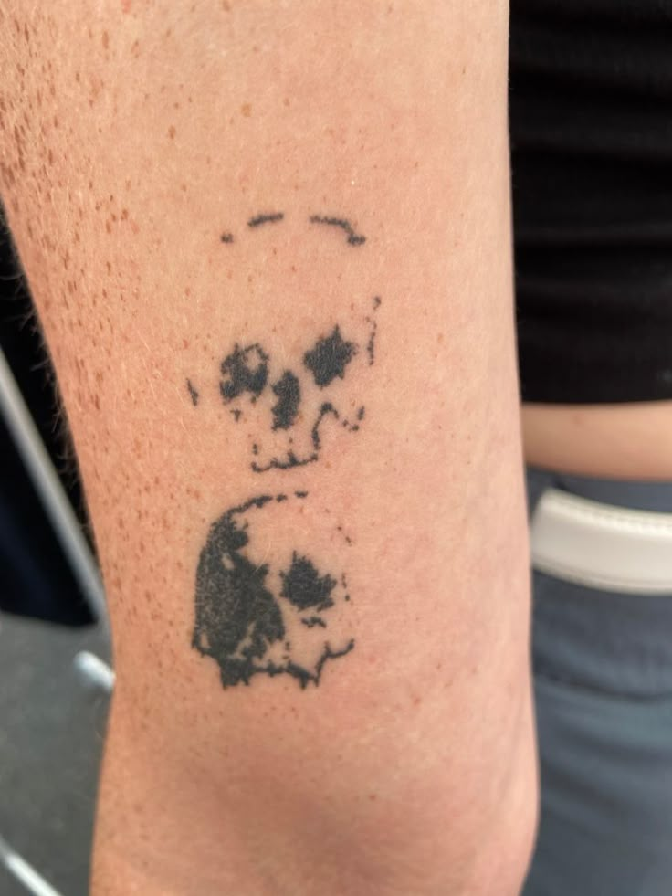 a person with a skull tattoo on their arm and the image of a panda bear