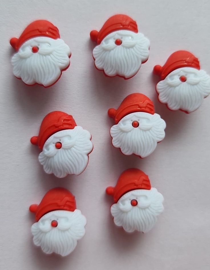 six red and white santa clause buttons on a white surface