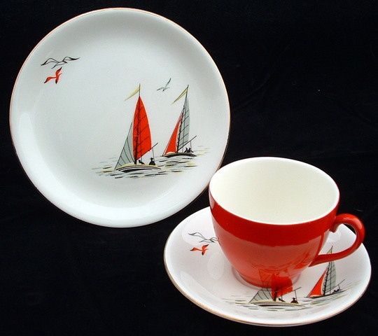 two red cups and saucers with sailboats on them sitting next to each other