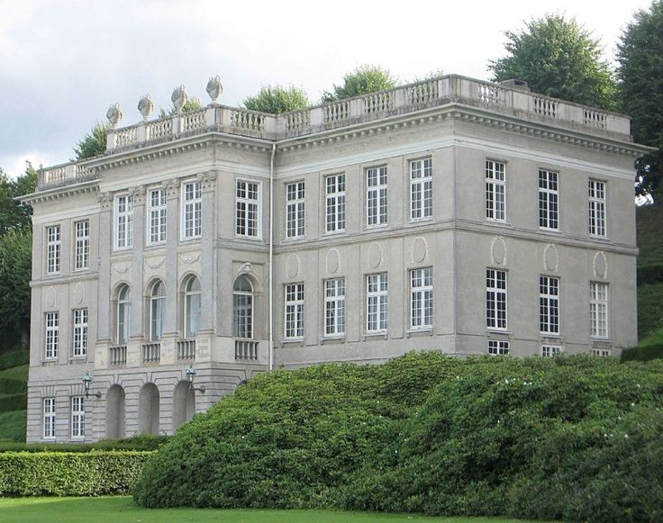 a large white building sitting on top of a lush green field