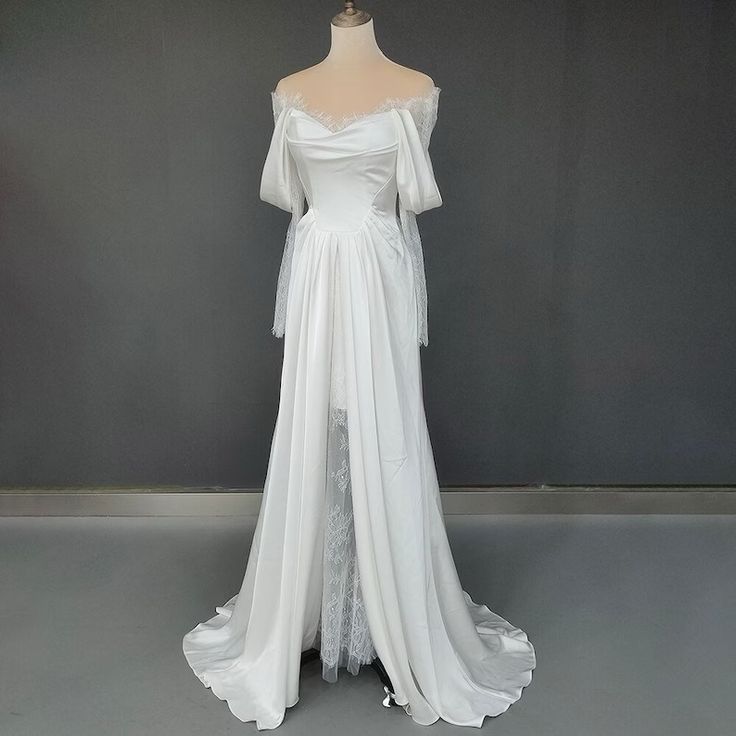 a white wedding dress with an off the shoulder neckline and long sleeves on display