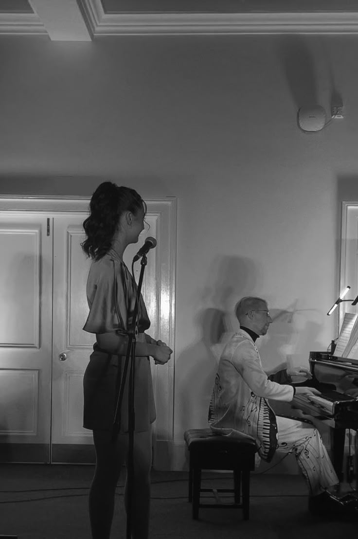 a woman standing in front of a piano next to a man