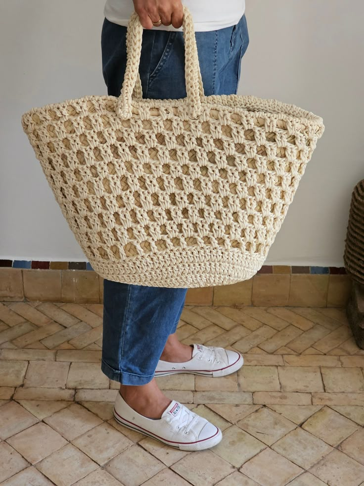 a woman is holding a crocheted tote bag