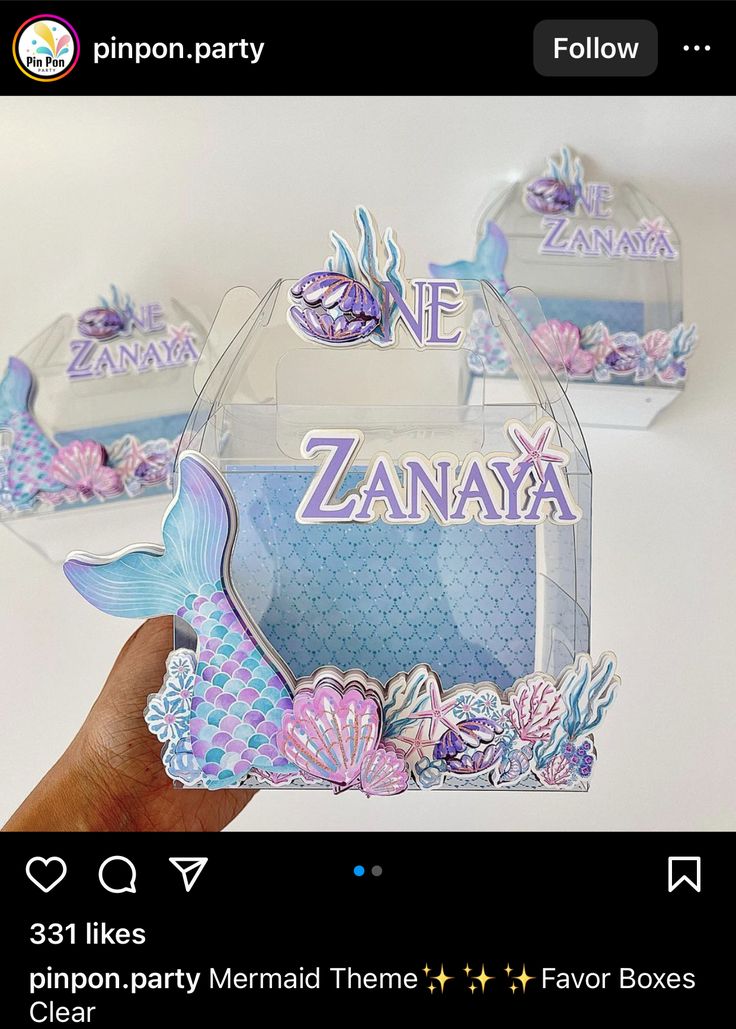 someone is holding up two little boxes with mermaid decorations on them and the words one zana