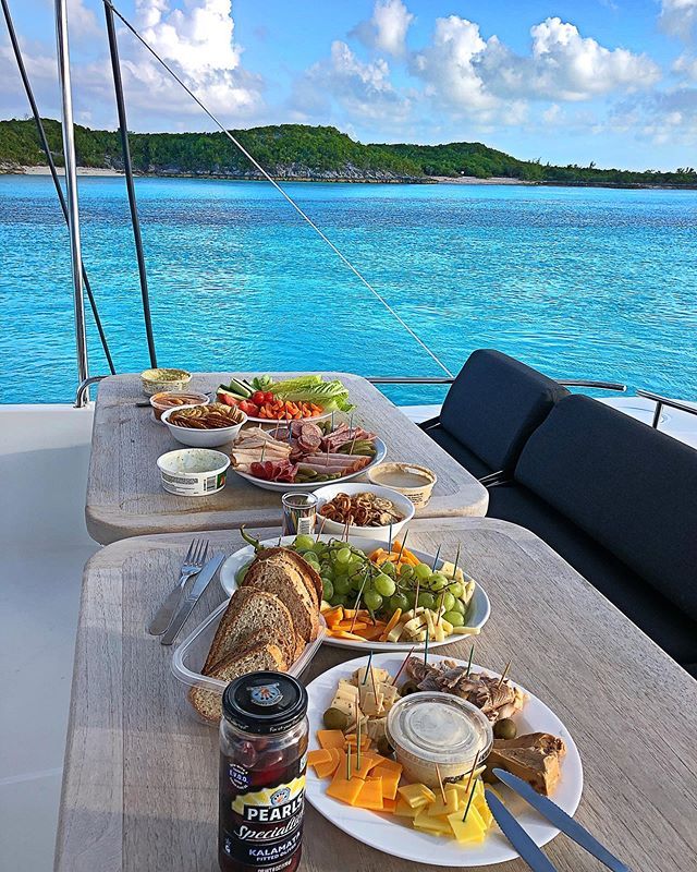 plates of food sit on the deck of a boat with blue water in the background