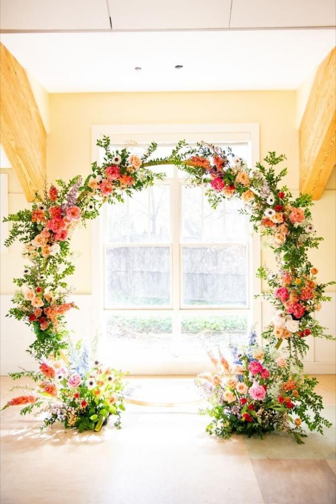 an archway with flowers and greenery in front of a window