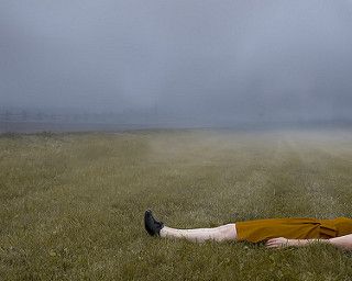 a woman laying on the ground in a field with her legs spread out and head down