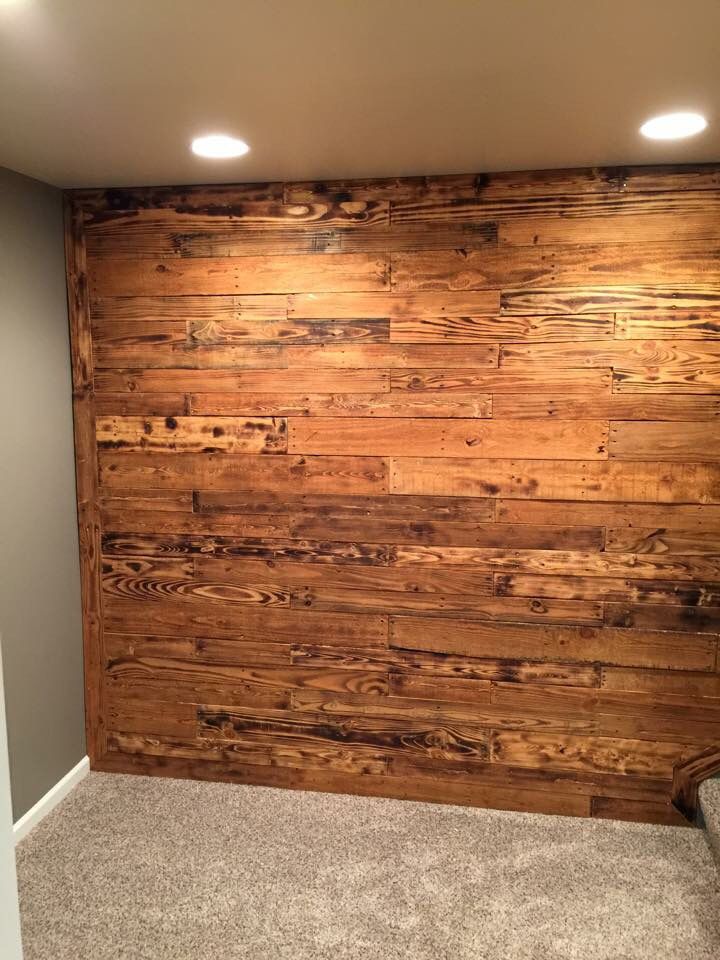 an empty room with wood paneling and carpeted walls in the corner is lit by two recess lights