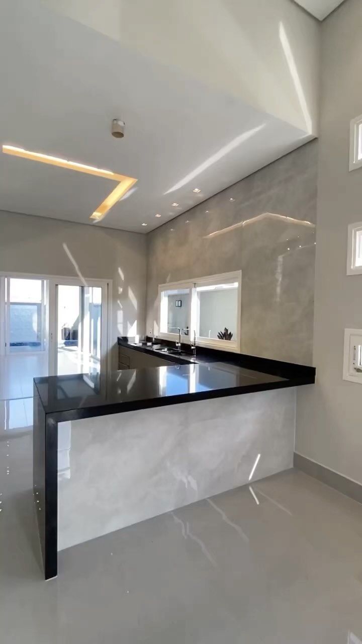 an empty kitchen with white walls and black counter tops in the center of the room