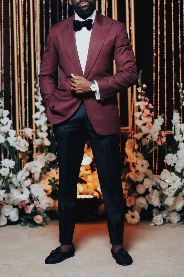 a man in a tuxedo standing next to flowers