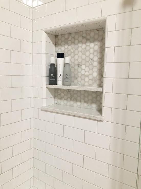 a white tiled shower with shelves above it