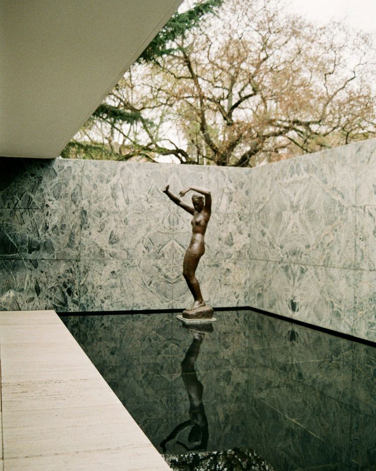 a statue is in the middle of a pool with water reflecting it's surface