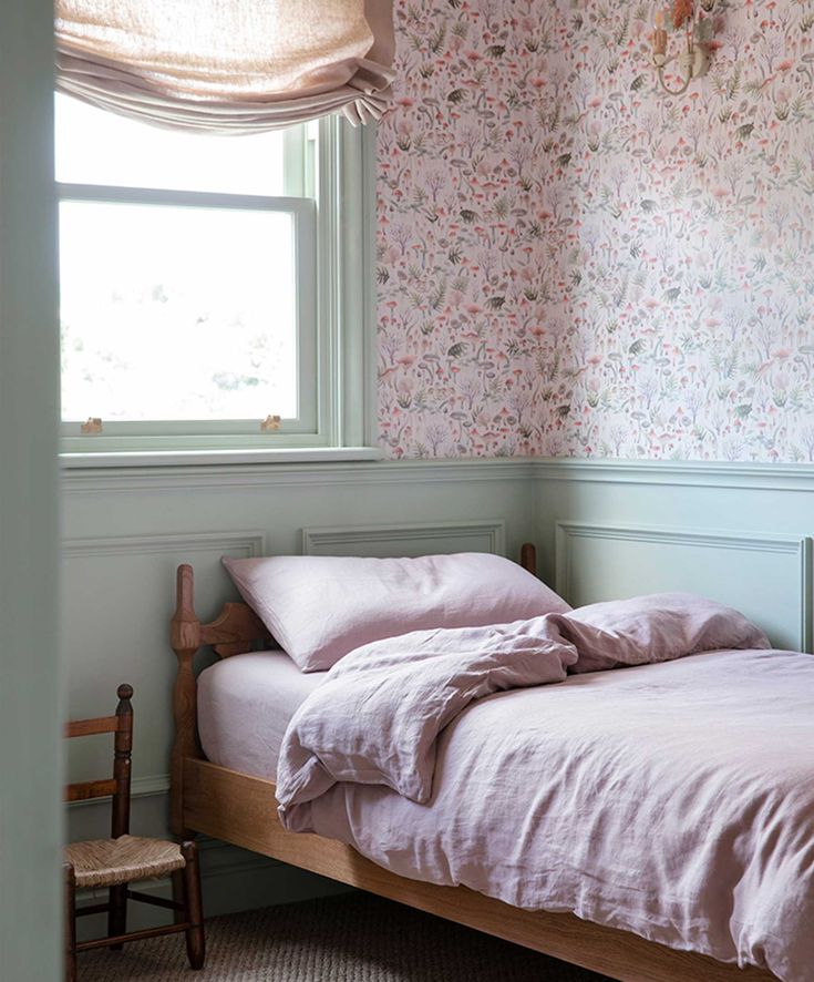 a bed sitting in a bedroom next to a window with flowers on the wall behind it