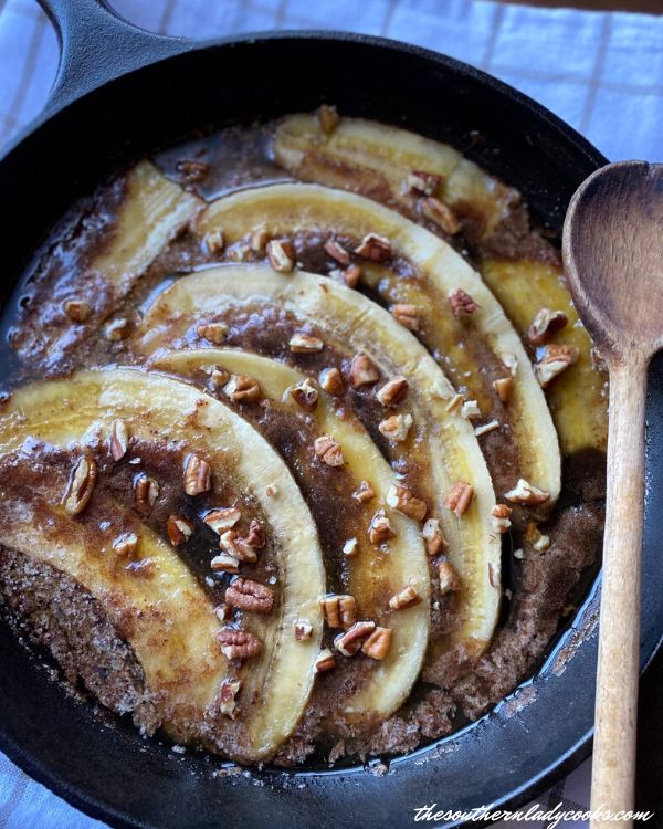 sliced bananas and pecans in a cast iron skillet on a white table cloth