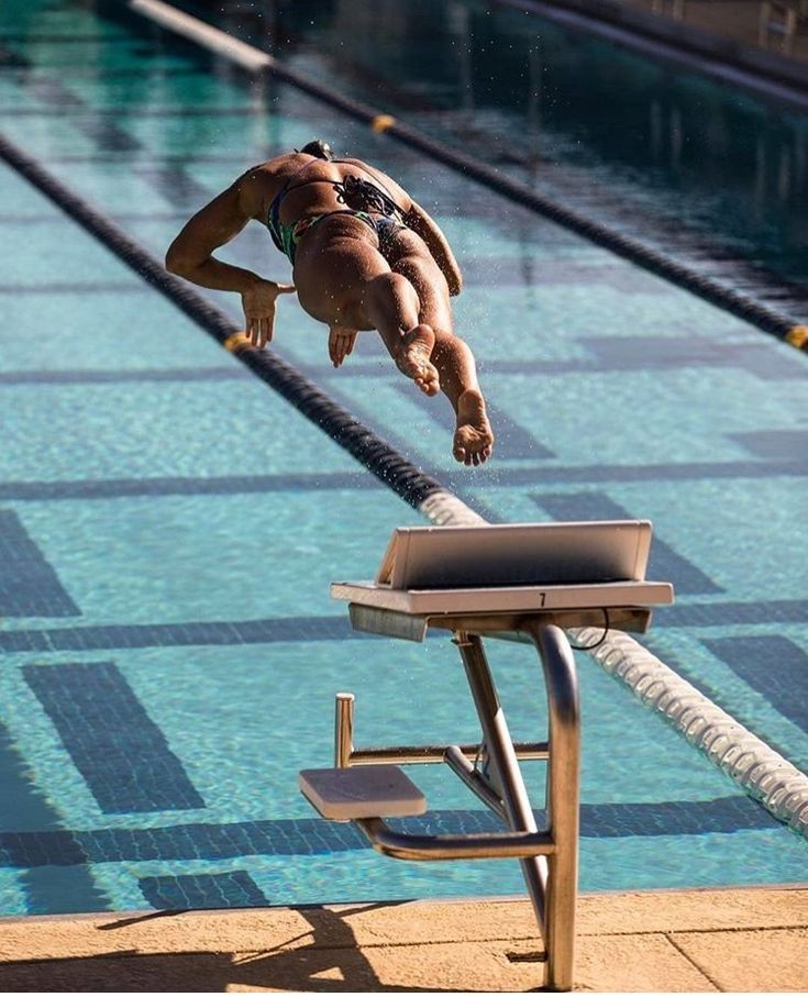 a man diving into a swimming pool from the edge of a diving board in mid air