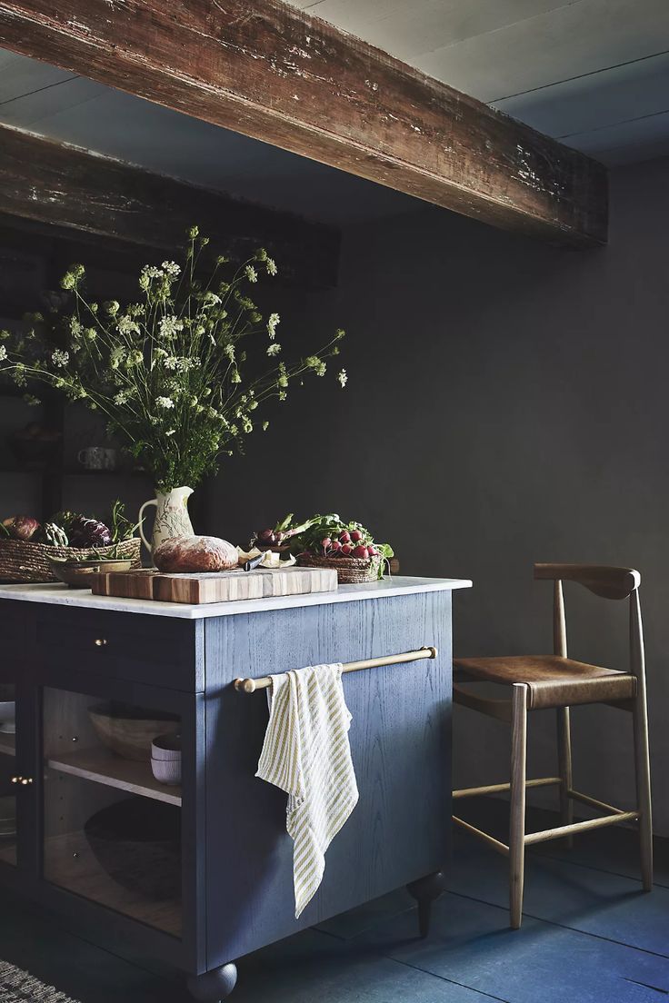 a kitchen island with flowers on it in front of a chair and potted plant