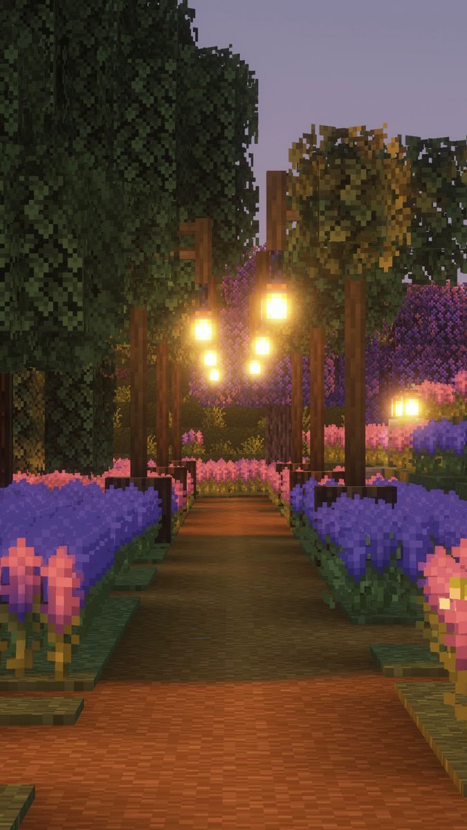 an image of a park at night with flowers in the foreground and lights on