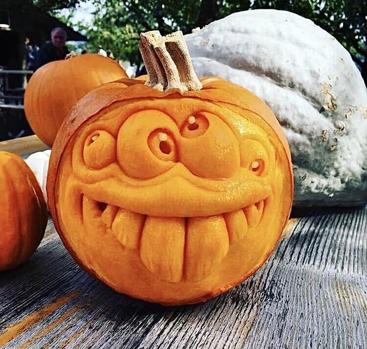 an orange carved pumpkin sitting on top of a wooden table next to other pumpkins