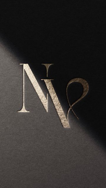 the letter n is made up of silver and gold foil on a black background with a shadow