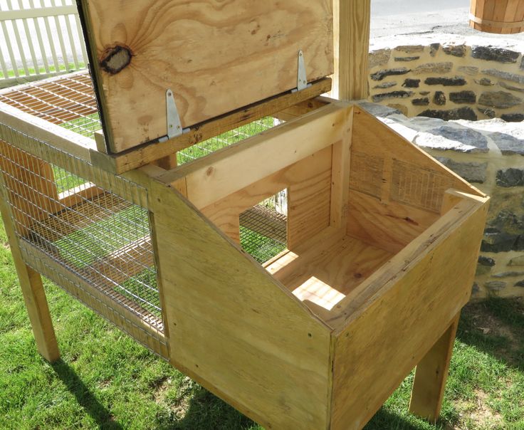 a wooden box sitting on top of green grass next to a stone wall and fence