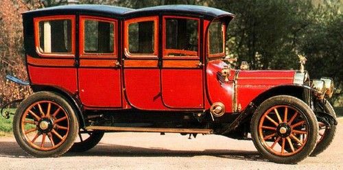 an old red car is parked on the side of the road in front of some trees