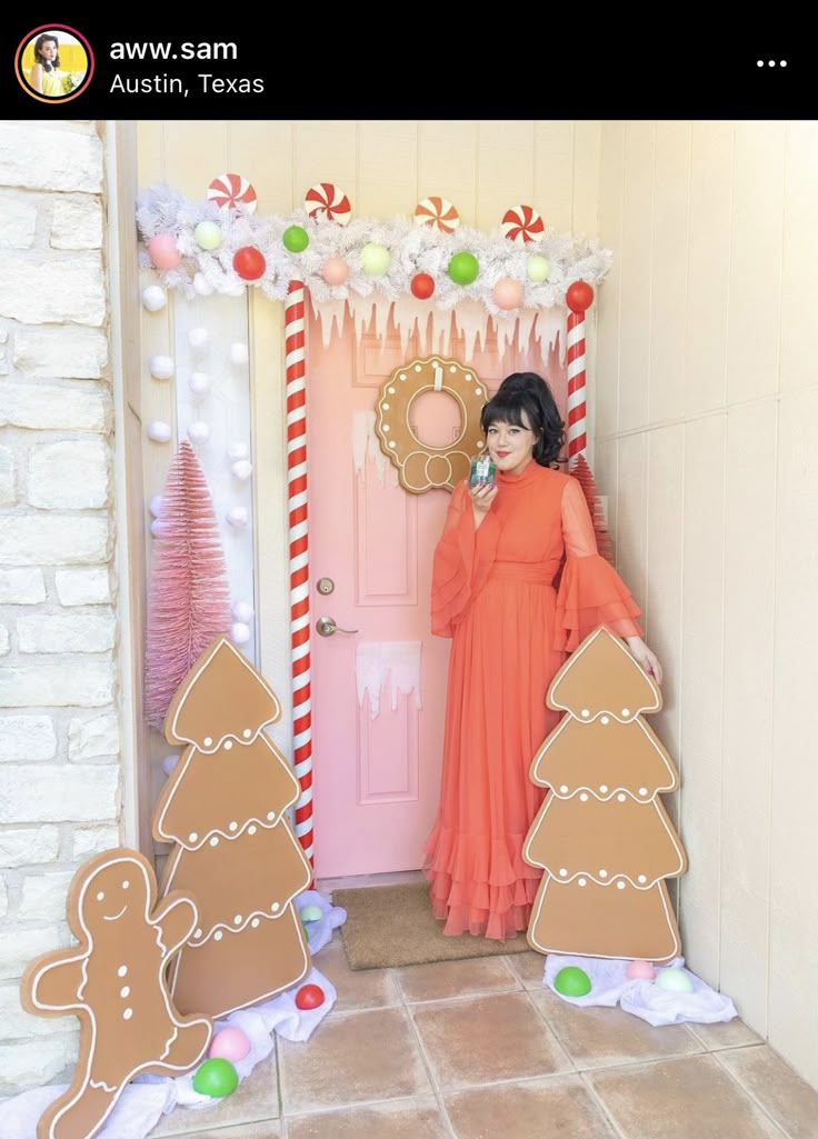 a woman standing in front of a door decorated with gingerbreads and christmas decorations