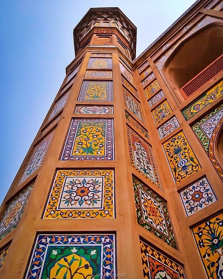 an ornate building with colorful tiles on it's side and a blue sky in the background