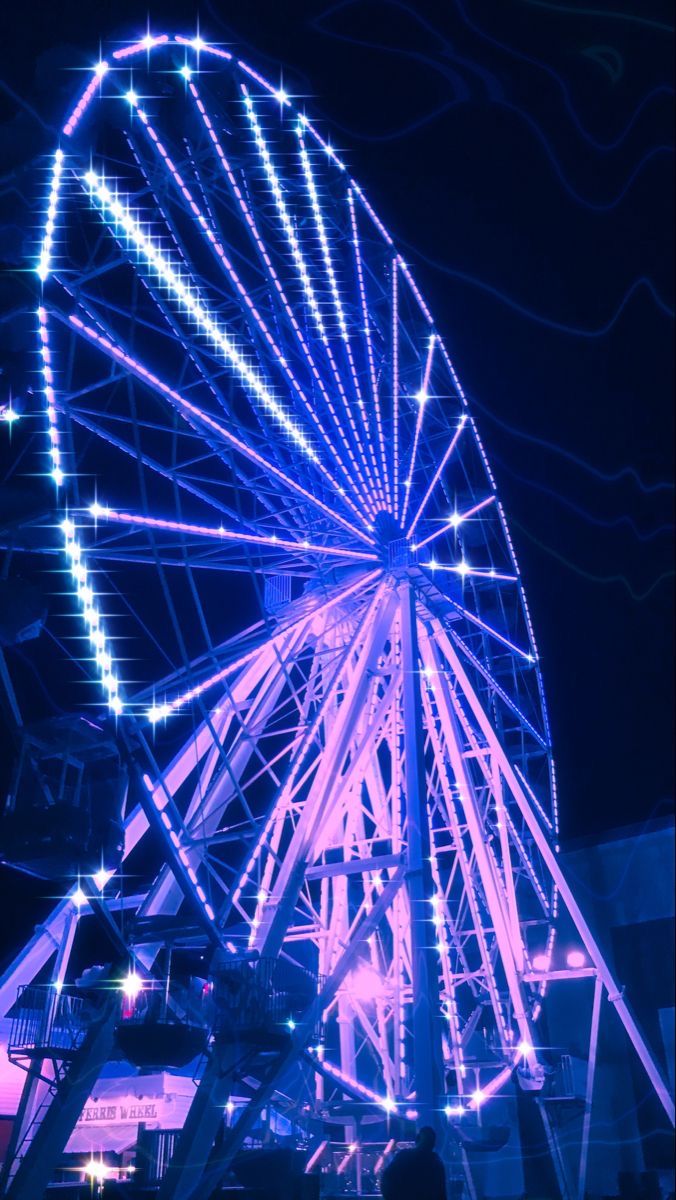 the ferris wheel is lit up at night