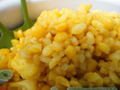 a white bowl filled with yellow rice and green beans on top of a wooden table